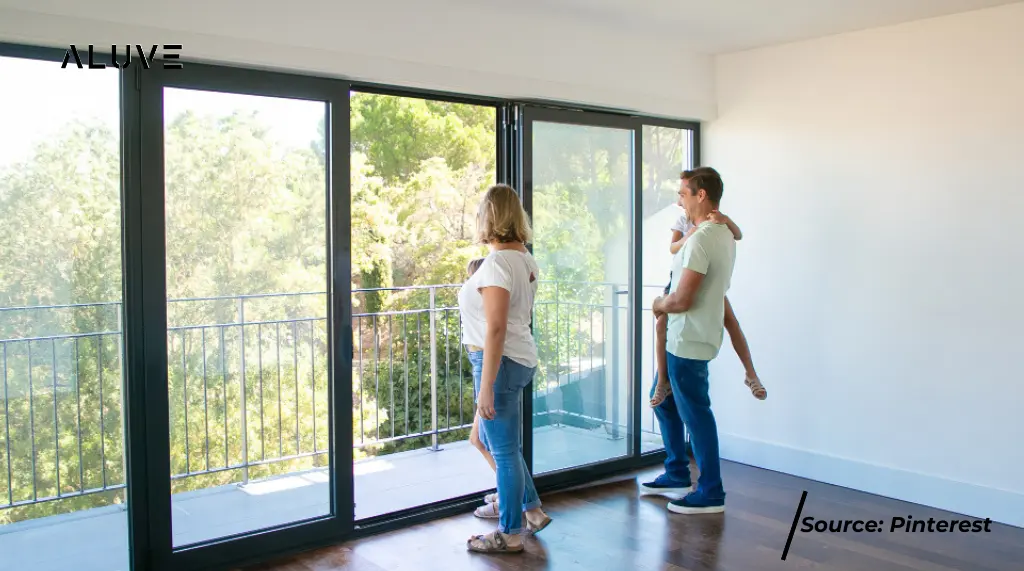 Keluarga yang sedang menatap ke luar rumah dengan pintu sliding aluminium hitam di depannya