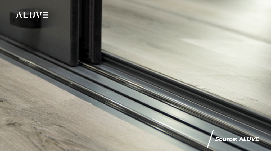 Pintu sliding alumiium warna hitam dengan fokus foto pada rail sliding.
